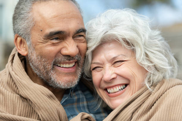 istock Senior couple wrapped in a blanket on a beach 1151287588