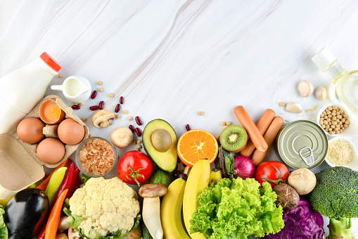 Top view of mixed  healthy food ingredients including colorful vegetables and fruits on marble kitchen countertop background