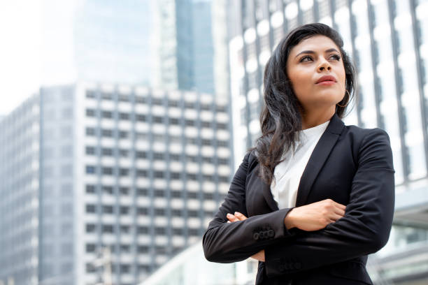 Powerful Latin businesswoman leader standing with arm crossed Powerful Latin businesswoman leader standing with arm crossed in city office building background powerful women stock pictures, royalty-free photos & images