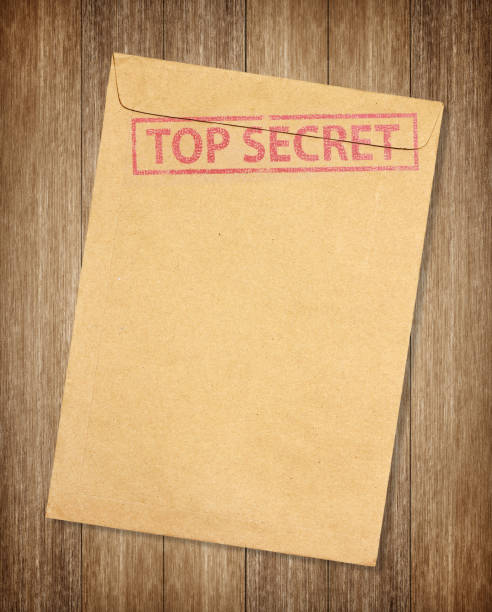 istock Brown envelope with top secret stamp isolated on on wood background 1151302161