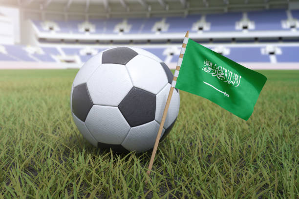 Saudi Arabia flag in football stadium field with soccer ball on grass stock photo