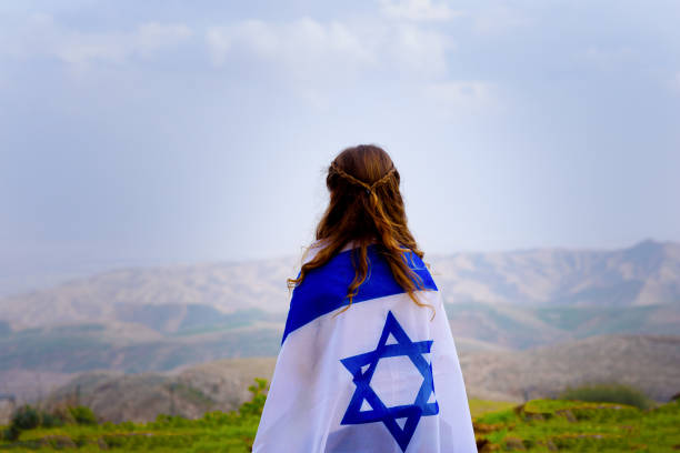 Israeli jewish little girl with Israel flag back view. Little patriot jewish girl standing and enjoying great view on the sky, valley and mountains with the flag of Israel wrapped around her. Memorial day-Yom Hazikaron and Yom Ha'atzmaut concept. gaza strip photos stock pictures, royalty-free photos & images