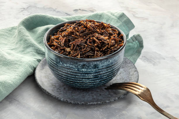Cooked wild black rice in a bowl, with a fork and a place for text