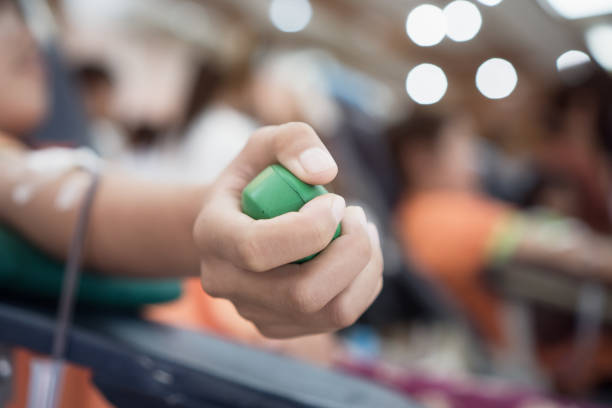 doação de doadores de transfusão de sangue com bola verde bouncy segurando na mão em hostpital para contribuir para pacientes humanos de pessoas homem doar voluntário. usado para várias condições médicas para substituir - hostpital - fotografias e filmes do acervo