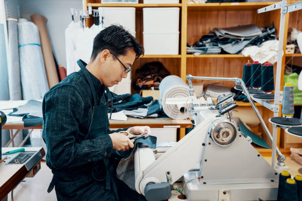 istock Mid adult man making denim jeans on a sewing machine at a textile studio 1151329179