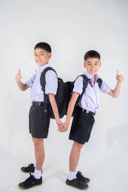 istock Little Asian sibling boys in student uniform pose together on white background 1151331487
