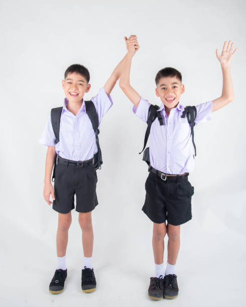 istock Little Asian sibling boys in student uniform pose together on white background 1151331593