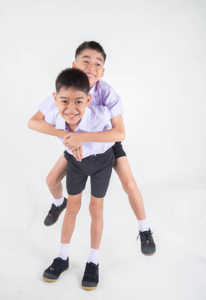 istock Little Asian sibling boys in student uniform pose together on white background 1151331701