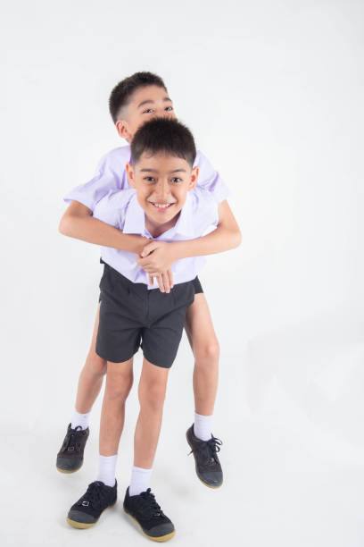 istock Little Asian sibling boys in student uniform pose together on white background 1151331729