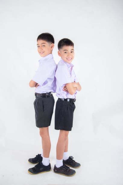 istock Little Asian sibling boys in student uniform pose together on white background 1151331785