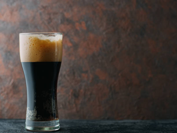 istock Craft dark beer porter in a glass on a brown dark background with copyspace 1151332128