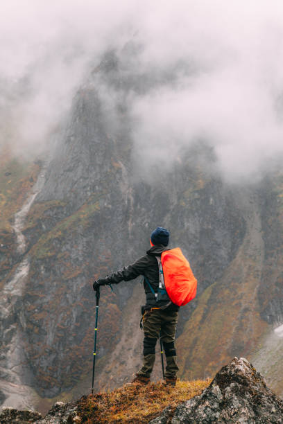 istock tourist standing under cliff in mountains 1151339325