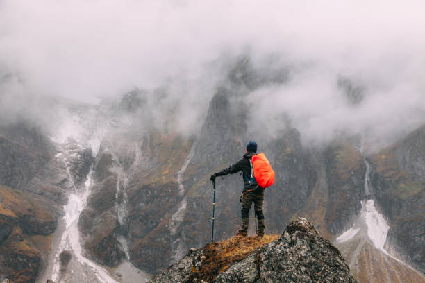 istock tourist standing under cliff in mountains 1151339443