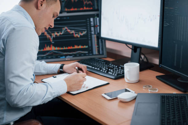 istock New points. Man working online in the office with multiple computer screens in index charts 1151342483