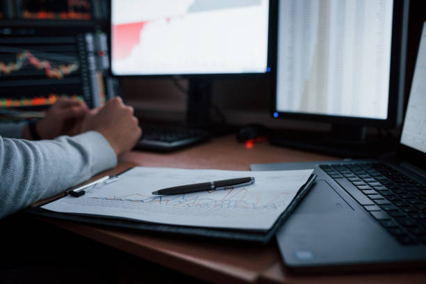 istock Close up view. Man working online in the office with multiple computer screens in index charts 1151342546