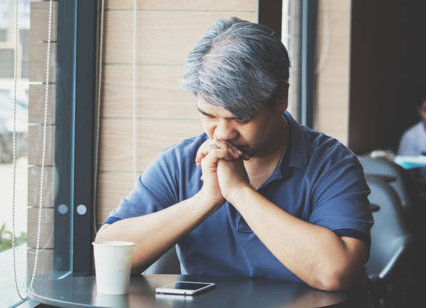 istock Stressed tired young Asian middle-aged man,elderly man take hand on head feeling depression and exhausted sitting by the window at coffee shop,grey hair man ,Family issues. 1151343511
