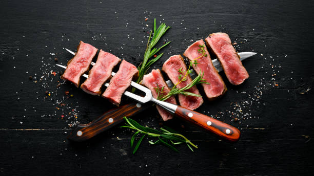 istock Grilled beef steak with a fork and a knife. Top view. Free space for your text. 1151346044