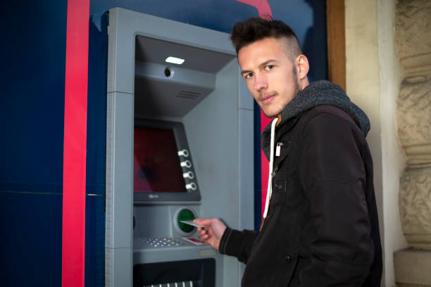 istock young man insert credit card to atm at night 1151346858
