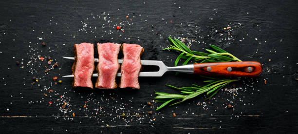 istock Juicy Steak on the fork with herbs and spices. Top view. Free space for your text. 1151346943