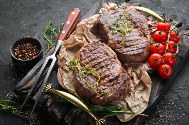 istock Grilled ribeye beef steak, herbs and spices on a dark table. Top view. Free space for your text. 1151347841