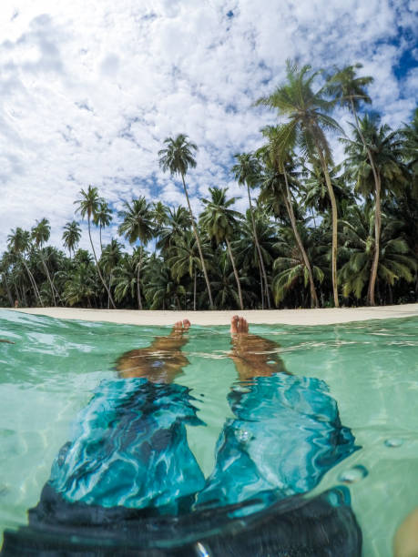 istock Man floating in sea under palm trees 1151352529