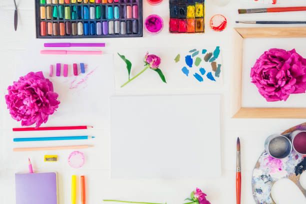 istock Topview workplace of creative artist mockup. Blank canvas with drawing materials and peony flowers on white background. Workshop, painting, drawing, inspiration, craft, creativity concept. Art therapy 1151353328