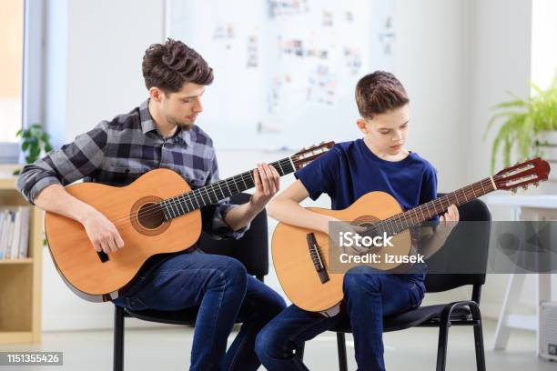 Guitarist Teaching Boy Plucking String Instrument Stock Photo - Download Image Now - 12-13 Years, 30-34 Years, Adult