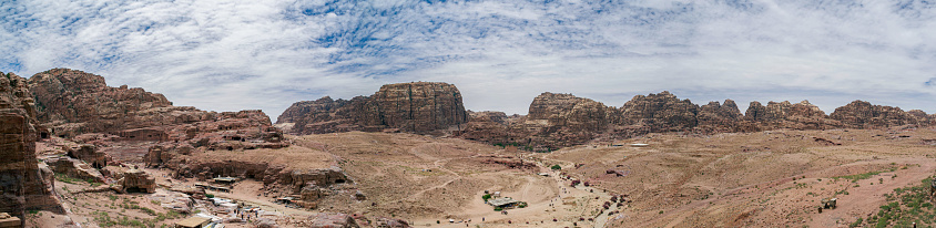 Panorama of the desert Jordan Petra with volumes in the distance and blue sky above. The temple and the tombs are visible.