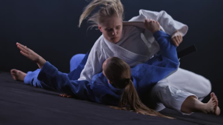 SLO MO Female judoka in white outfit throwing her opponent in blue on the floor