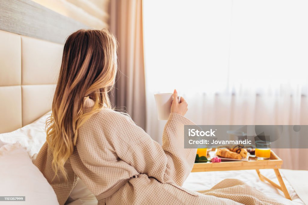 Beautiful woman laying and enjoying, breakfast in bed - Breakfast in bed, cozy hotel room. concept Hotel Stock Photo