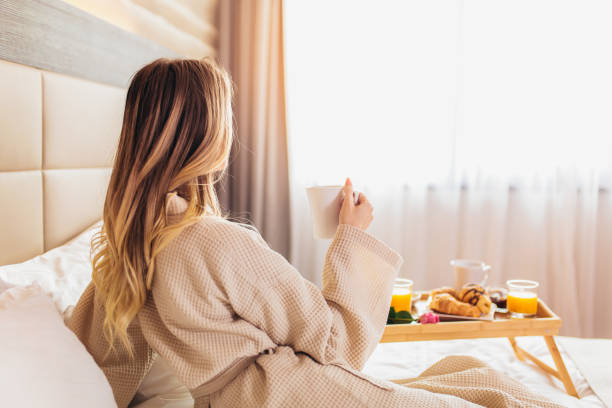 Beautiful woman laying and enjoying, breakfast in bed - Breakfast in bed, cozy hotel room. concept bathrobe photos stock pictures, royalty-free photos & images