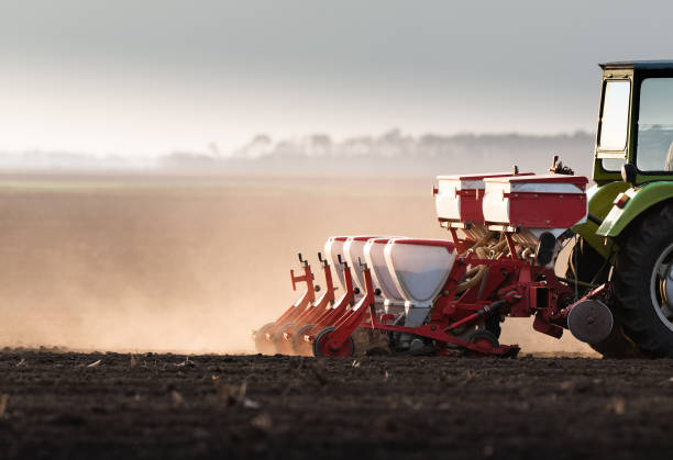 istock Farmer with tractor seeding  crops at agricultural field 1151366974