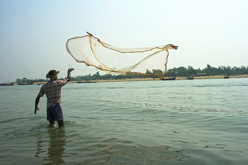 Fisherman casting nets in River