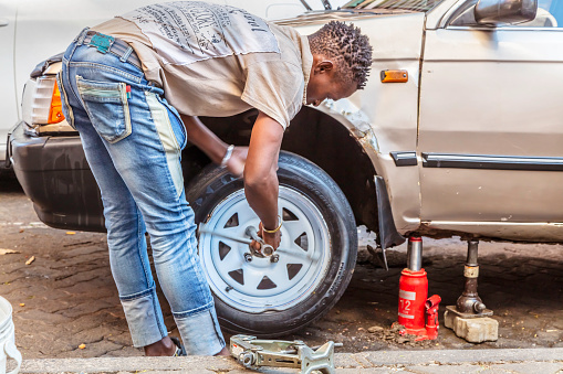 Man doing a wheel change in the streets of Hillbrow, Johannesburg. Hillbrow is a densely populated residential area in Johannesburg where most of the residents are migrants from the townships, rural areas and the rest of Africa, and mostly living in real poverty.