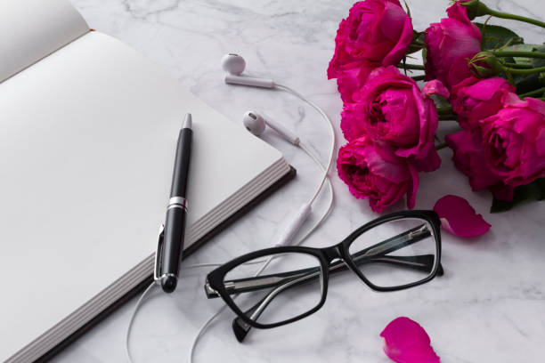 istock Headphones, glasses and roses bouquet with blank notepad on white background 1151369475