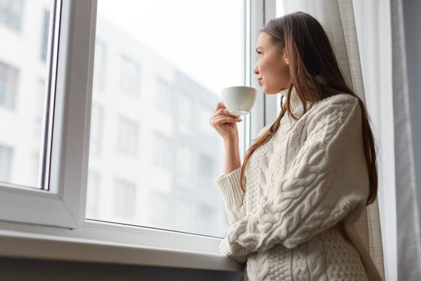 istock Relaxing dreaming woman with drink at window 1151370735