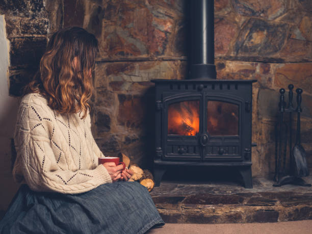 istock Woman in white jumper by fireplace with mug 1151375935