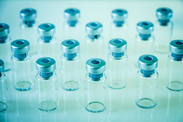 Glass ampoules with liquid on a neon background. Coronavirus vaccine. Ampoules for use in cosmetology