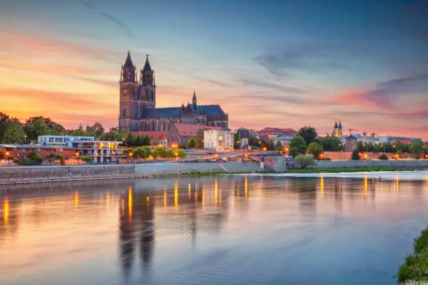 Cityscape image of Magdeburg, Germany with reflection of the city in the Elbe river, during sunset.