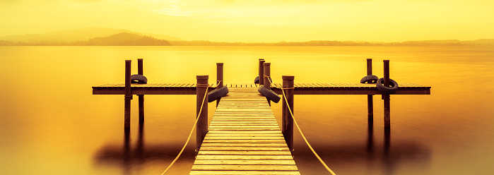 Wooden jetty on the lake in trend colors.  Clouds in the sky. Long Exposure. Switzerland.