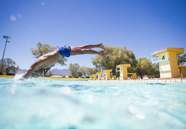 High Angle View Of Mid Adult Woman Wearing Bikini While Jumping In Swimming Pool