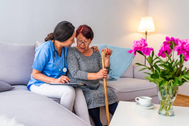 Elderly woman holding hands on walking stick and listening doctor in light room Smiling senior woman with walking stick and helpful caregiver holding her hand. Elderly woman holding hands on walking stick and listening doctor in light room Travel Nurse stock pictures, royalty-free photos & images