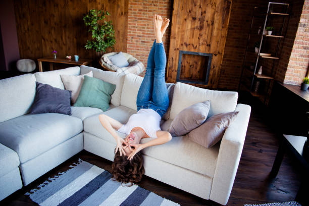 istock Above high angle view of her she nice attractive lovely cheerful cheery glad optimistic wavy-haired girl lying on divan crossed legs having fun at industrial loft wooden brick style interior 1151385236