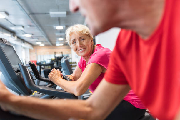 istock Two happy senior people on bikes in gym 1151385647