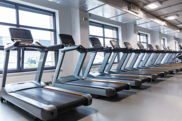 Row of treadmills in a gym Gym interior with treadmills in a row. Exercising machines in modern health club. treadmill stock pictures, royalty-free photos & images