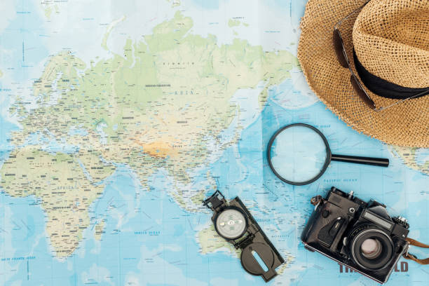 istock Top view of straw hat, compass, magnifier and film camera on world map 1151398962