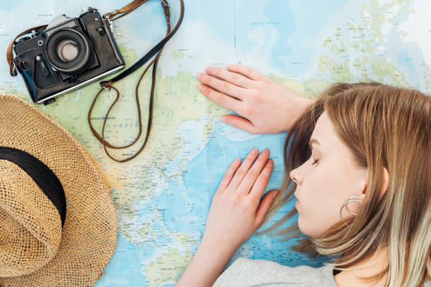 istock Woman with film camera and straw hat sleeping on world map 1151399018