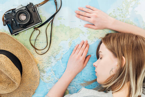 istock Woman with film camera and straw hat sleeping on world map 1151399070
