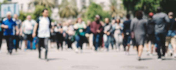 istock Unrecognizable people in bokeh walking along a street. Blurred image 1151399367
