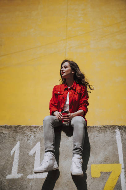 Young hipster smiling girl with coffee on parapet
